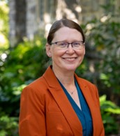 a woman in orange jacket and blue shirt